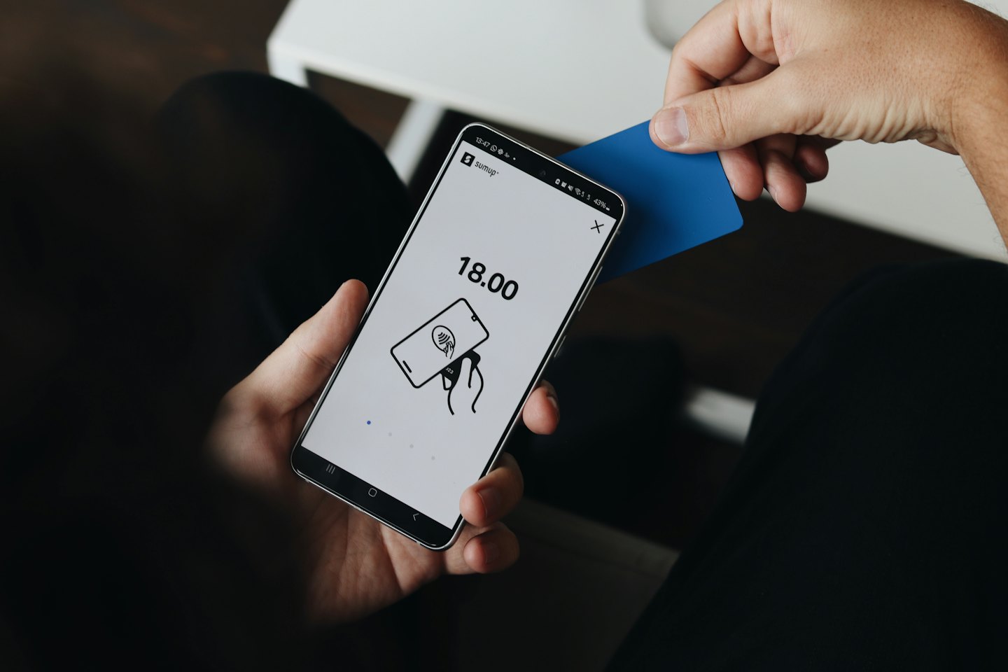 Hände halten ein Smartphone, das eine kontaktlose Zahlung abwickelt.